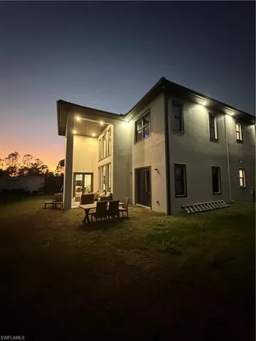 Rear view of house with a yard, stucco siding, and a patio