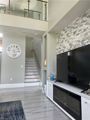 Living room with stairway, a high ceiling, and light wood-type flooring