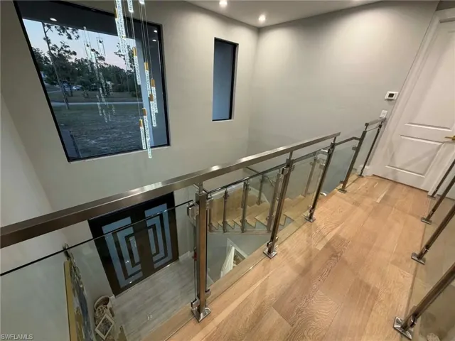 Staircase with wood finished floors and recessed lighting