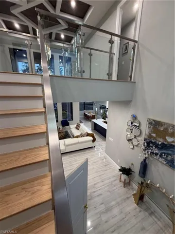 Stairs featuring coffered ceiling, wood finished floors, and a towering ceiling