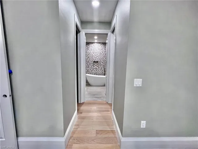 Hallway with light wood-type flooring and recessed lighting