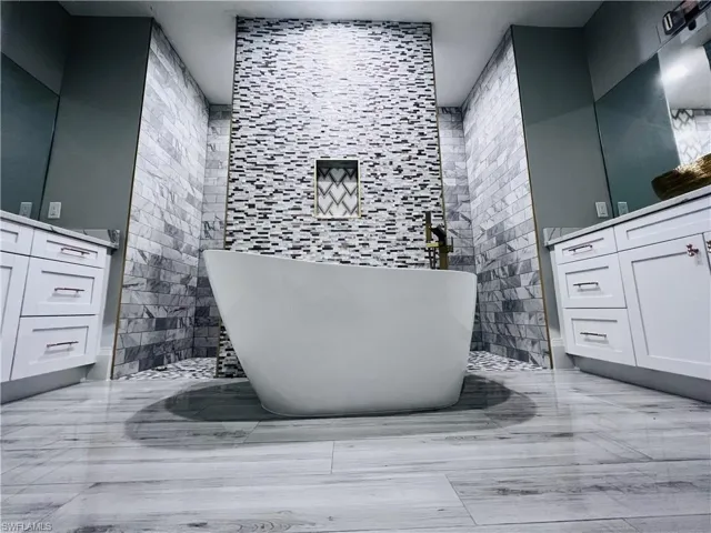 Full bathroom with vanity, a soaking tub, and tile walls