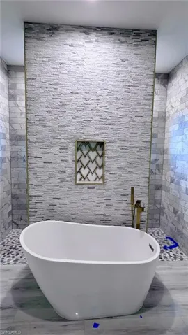 Bathroom with a soaking tub, tile walls, and tiled shower