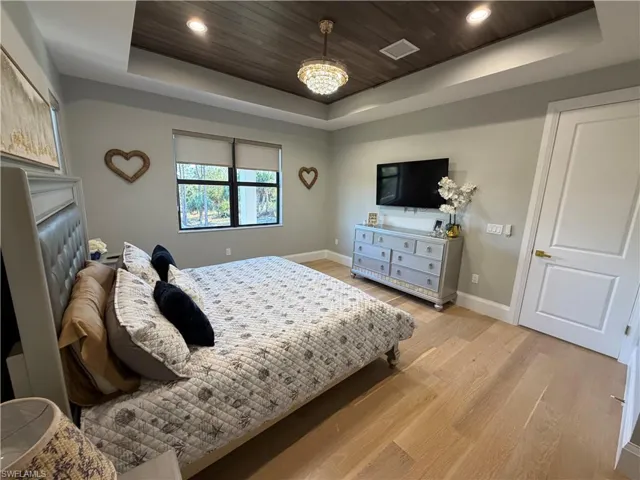 Bedroom featuring light wood-type flooring, wooden ceiling, recessed lighting, and a raised ceiling