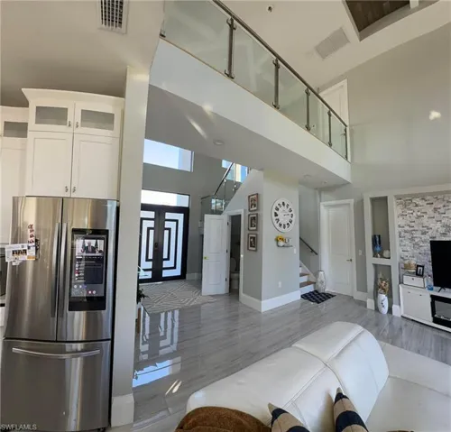 Kitchen with glass fronted cabinets, smart refrigerator, white cabinetry, open floor plan, and a high ceiling