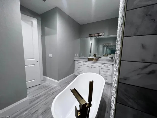 Full bath with a freestanding bath, vanity, and light wood finished floors