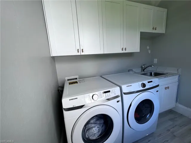 Laundry room with cabinet space, washing machine and clothes dryer, and light wood finished floors