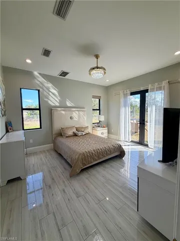 Bedroom with multiple windows, recessed lighting, wood tiled floors, and french doors