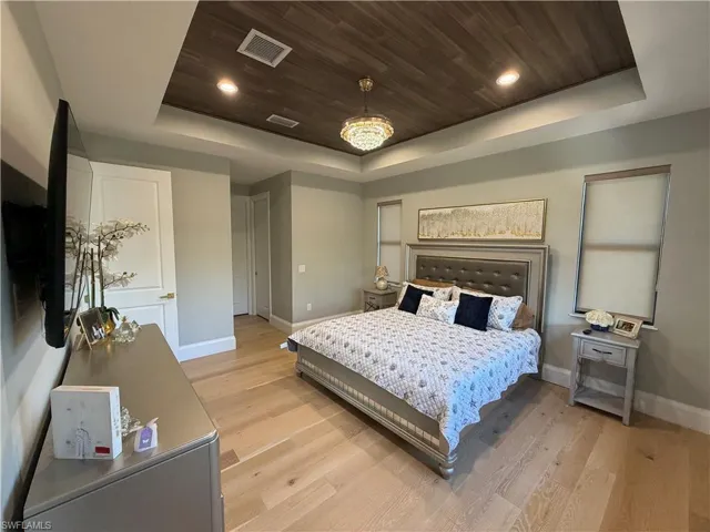 Bedroom featuring wood ceiling, light wood finished floors, a tray ceiling, and recessed lighting