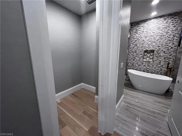 Bathroom with recessed lighting, light wood-style flooring, and a freestanding bath