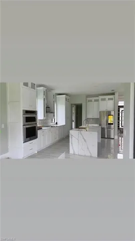 Kitchen with stainless steel appliances, glass insert cabinets, and white cabinetry