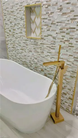 Full bath with a freestanding bath, tile patterned floors, and tile walls