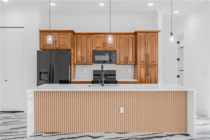 Kitchen with light marble finish floors, brown cabinets, light stone countertops, recessed lighting, and decorative backsplash