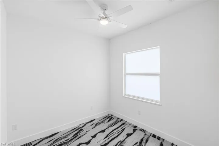 Empty room featuring a ceiling fan and baseboards