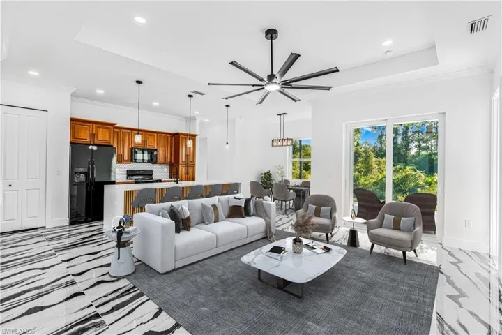 Living room with ornamental molding, a ceiling fan, recessed lighting, and a tray ceiling