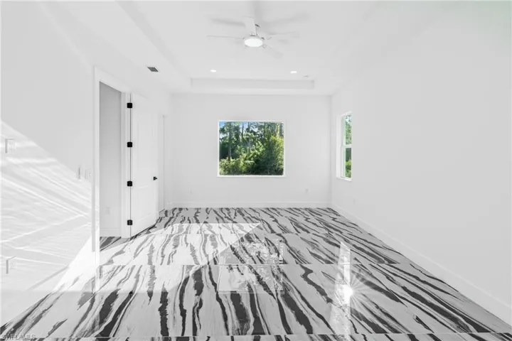 Unfurnished bedroom with a ceiling fan, a tray ceiling, and recessed lighting
