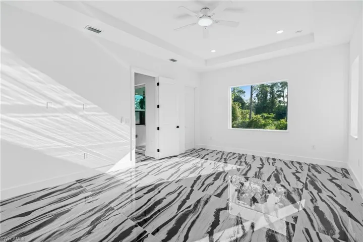 Unfurnished bedroom with a tray ceiling, a ceiling fan, and recessed lighting