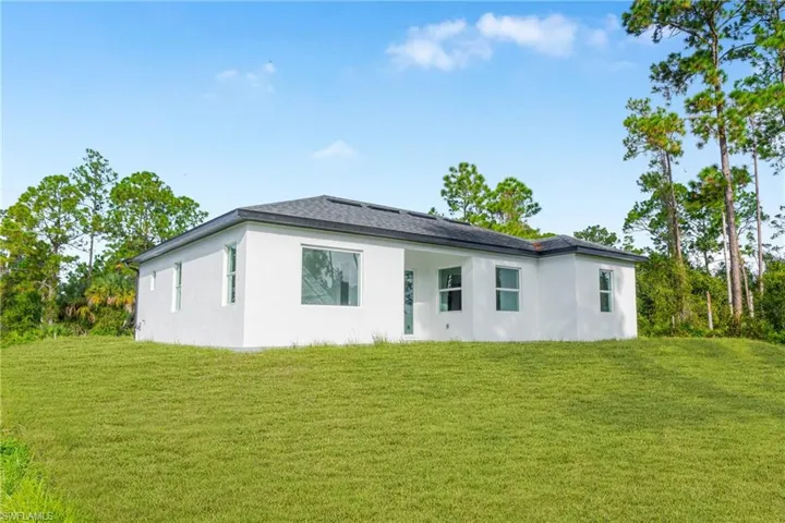 Rear view of property with a lawn and stucco siding