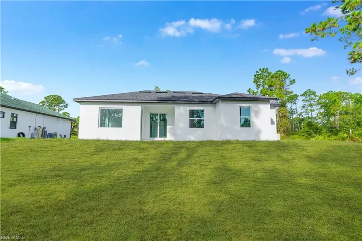 Rear view of house with stucco siding and a yard
