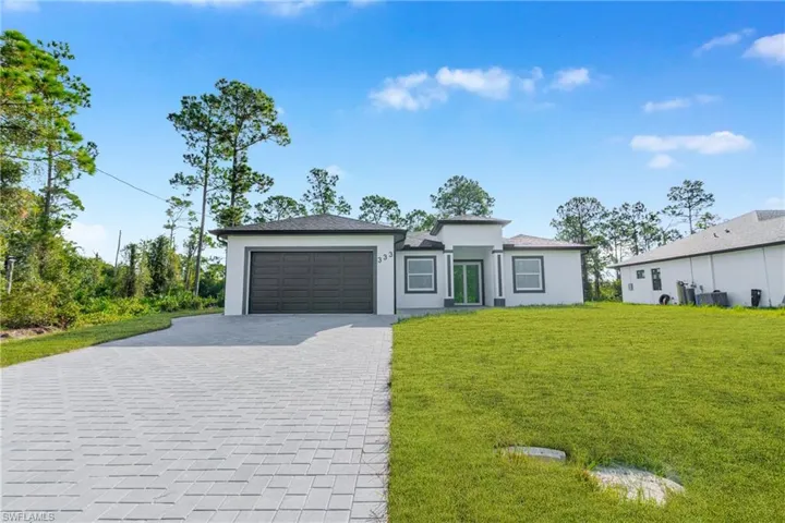 Prairie-style home with decorative driveway, a front lawn, an attached garage, and stucco siding