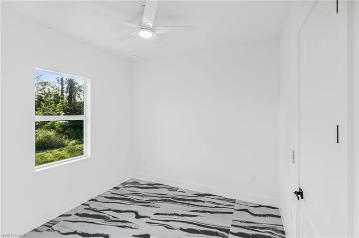 Spare room featuring a ceiling fan and baseboards