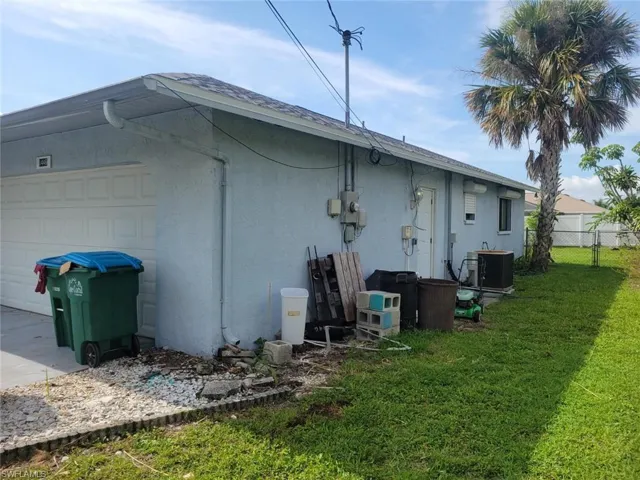 View of side of property featuring a garage, a yard, and central air condition unit