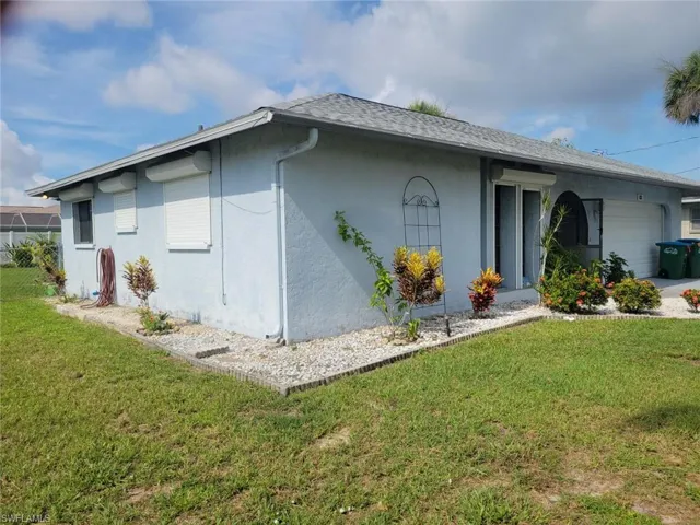 View of side of home with a garage and a lawn