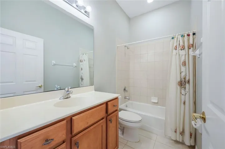 Bathroom with vanity, toilet, tile patterned floors, and shower / bathtub combination with curtain