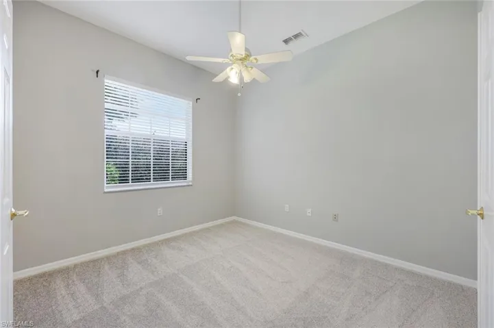 Carpeted spare room featuring ceiling fan and baseboards