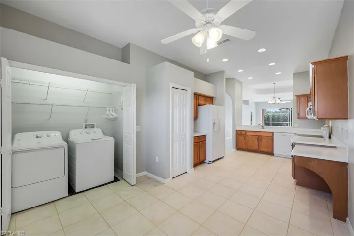 Laundry room featuring washer and clothes dryer, a ceiling fan, recessed lighting, a chandelier, and light tile patterned flooring