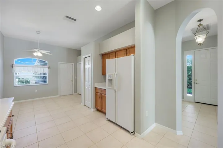 Kitchen with white fridge with ice dispenser, brown cabinets, and plenty of natural light