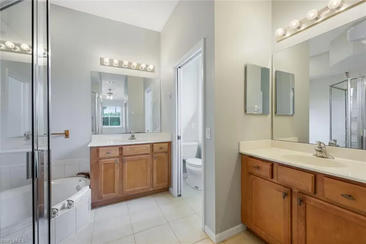Full bath with vanity, a stall shower, tile patterned floors, toilet, and a bath
