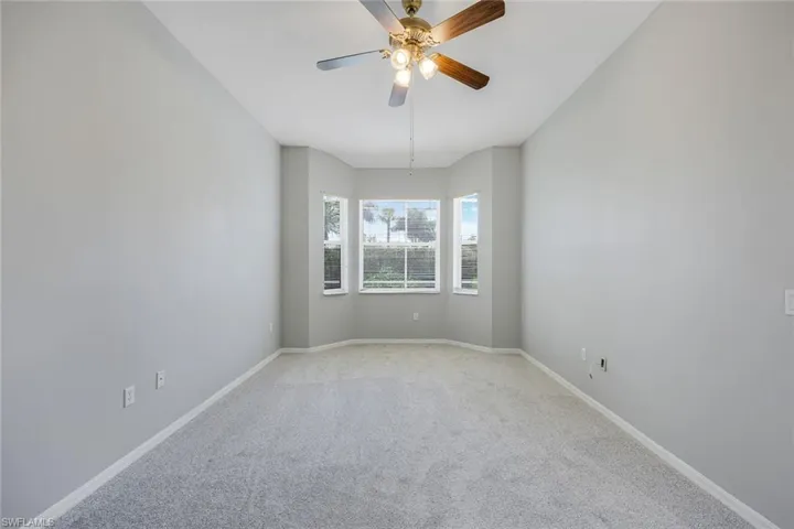 Unfurnished room featuring light colored carpet, a ceiling fan, and baseboards
