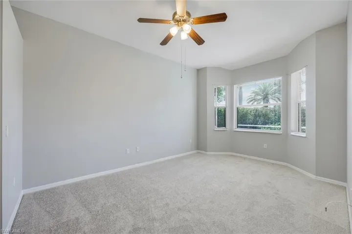 Carpeted empty room with baseboards and ceiling fan