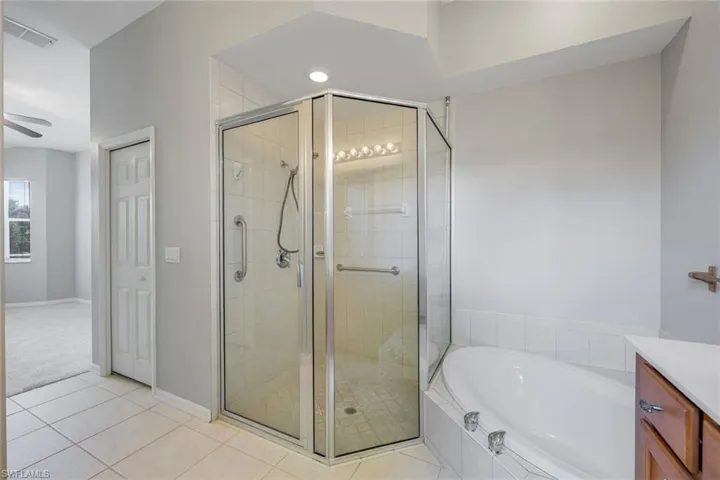 Bathroom featuring a bath, a shower stall, tile patterned flooring, and vanity