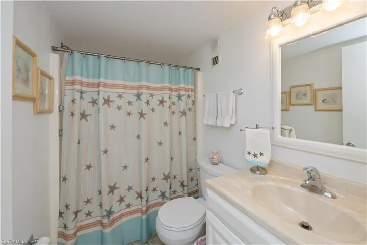 Full cheerful guest bathroom featuring shower / tub combo with tiled floor white vanity and  neutral colored Cultured marble top