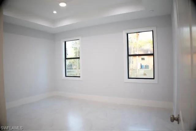 Unfurnished room featuring a raised ceiling and recessed lighting