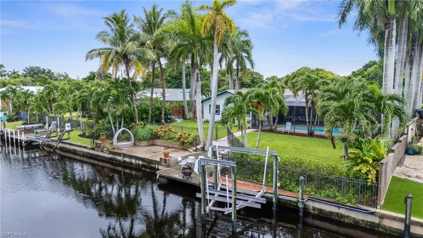 View of dock with a water view, a yard, a lanai, and a swimming pool