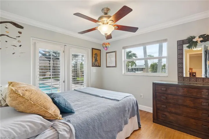 Bedroom featuring light wood-type flooring, ornamental molding, access to exterior, and ceiling fan