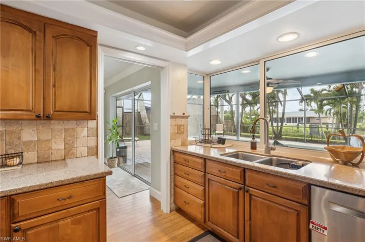 Kitchen with a wealth of natural light, light hardwood / wood-style flooring, sink, and light stone countertops