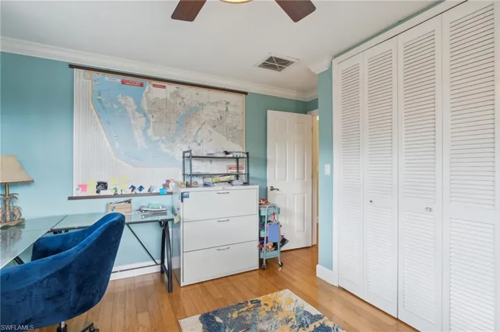 Office space with light wood-type flooring, crown molding, and ceiling fan