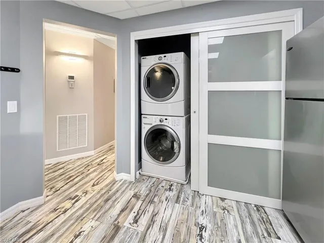 Kitchen with stacked washer and clothes dryer and light hardwood / wood-style floors