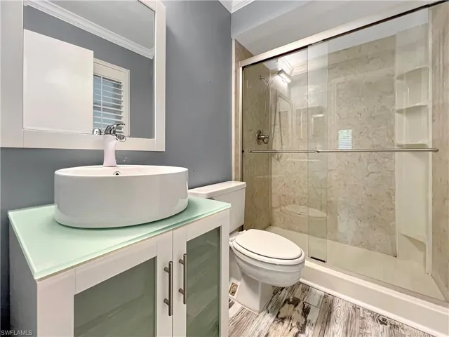 Bathroom featuring hardwood / wood-style floors, an enclosed shower, toilet, and vanity