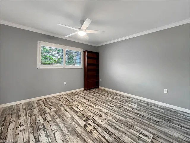 Guest room featuring ornamental molding, hardwood / wood-style flooring, and ceiling fan