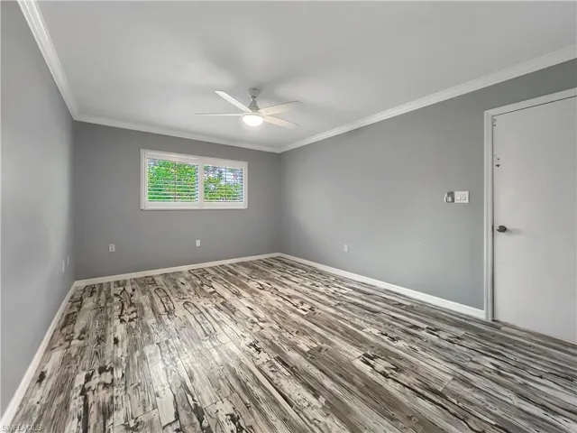 Primary bedroom with wood-type flooring, crown molding, and ceiling fan