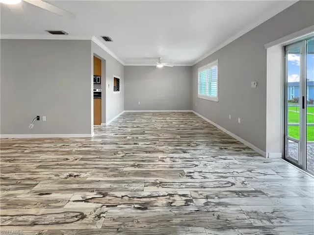 Great room with ornamental molding, light wood-type flooring, and ceiling fan