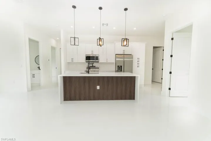 Kitchen with stainless steel appliances, light tile patterned flooring, white cabinetry, light countertops, and recessed lighting