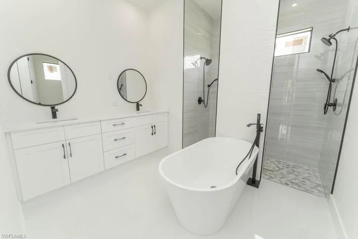 Full bath with tiled shower, a soaking tub, and double vanity