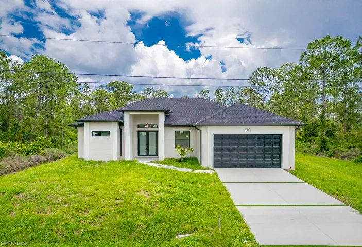 Prairie-style home featuring stucco siding, a front yard, an attached garage, concrete driveway, and a shingled roof