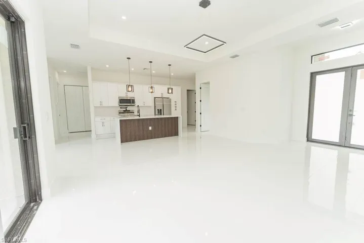 Unfurnished living room with recessed lighting, light tile patterned flooring, a sink, and a raised ceiling